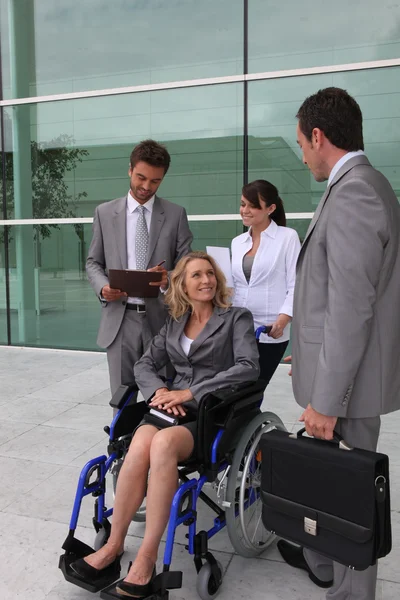 Imprenditrice su sedia a rotelle con colleghi fuori da un edificio per uffici — Foto Stock