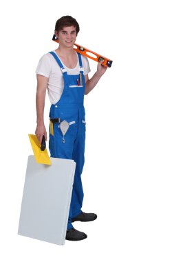 Young tradesman posing with his tools and materials clipart