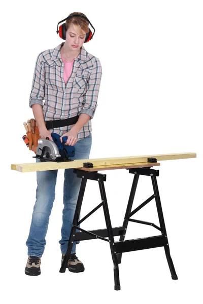 Vrouw met behulp van een cirkelzaag te snijden een houten plank — Stockfoto