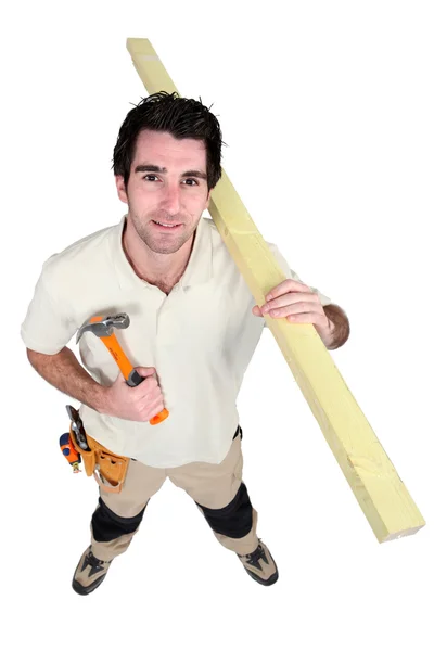 Handyman håller en hammare och bär en planka — Stockfoto