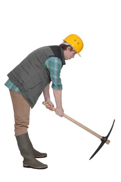 Un travailleur de la construction creusant avec une pioche . — Photo