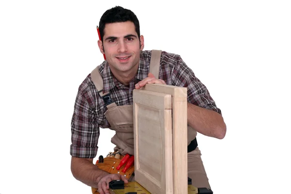 Un carpintero trabajando en la puerta de un armario . — Foto de Stock