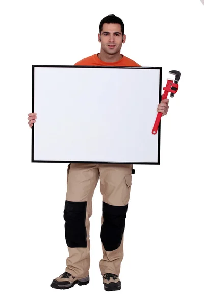 Hombre con una llave inglesa y una tabla en blanco para su mensaje — Foto de Stock