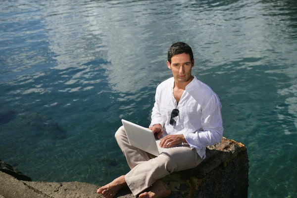 Yakışıklı bir adam onun laptop ile sahilde — Stok fotoğraf
