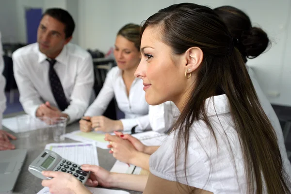 Žena pomocí kalkulačky na schůzi týmu office — Stock fotografie