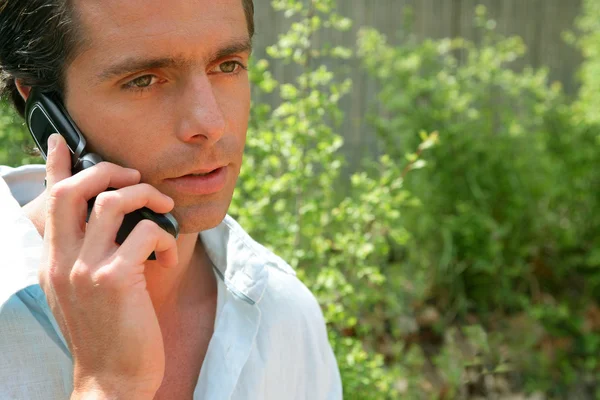 Man on the phone outdoors looking concerned — Stock Photo, Image
