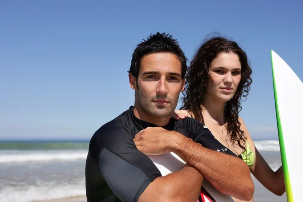 Пара стояла на пляже с досками для серфинга — стоковое фото