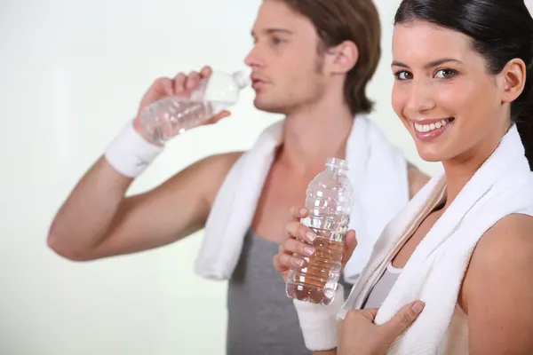 Спортивная женщина и мужчина питьевой воды на белом фоне — стоковое фото