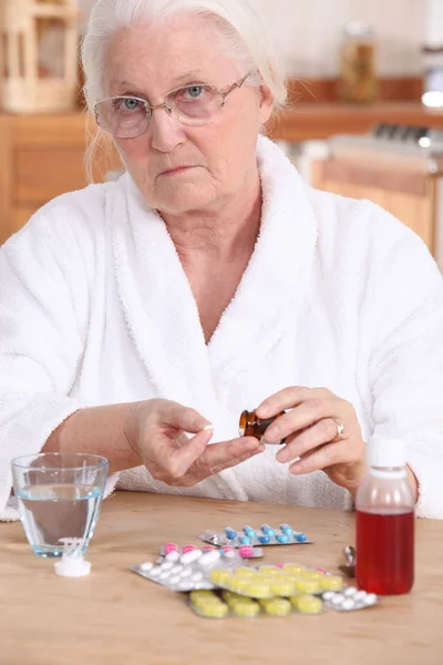 Unhappy elderly lady taking her medication — Stock Photo, Image