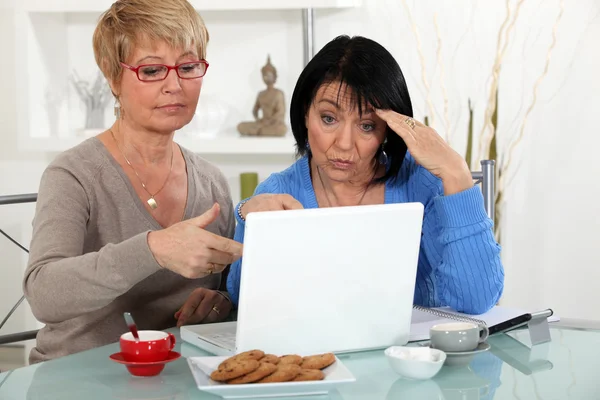 Older women puzzling over a laptop — Stock Photo, Image