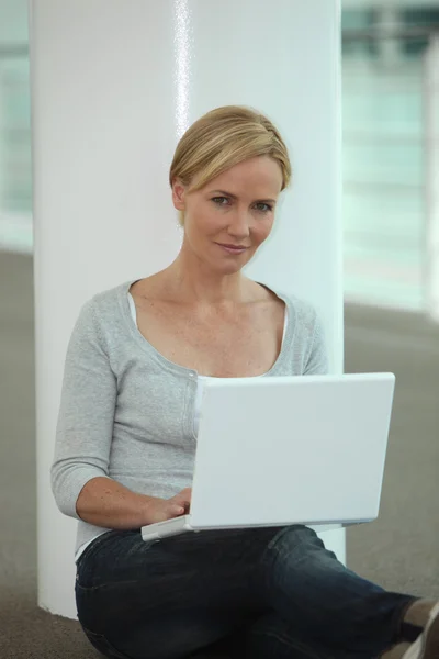 Женщина сидела рядом с колонкой, используя ноутбук — стоковое фото