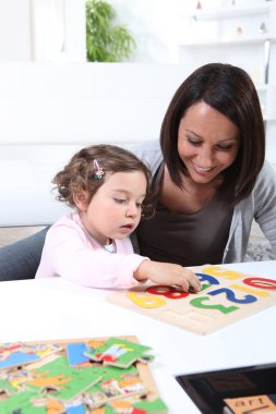 Mother and young daughter doing jigsaw puzzles clipart