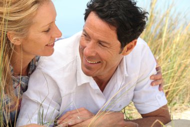 Couple looking into each other's eyes on the sand. clipart