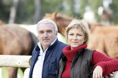 Couple standing next to horses clipart