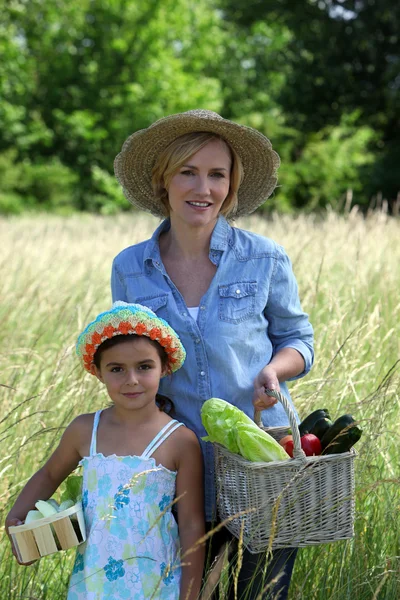 Mãe e filha carregando cestas cheias de legumes — Fotografia de Stock