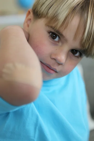 Niño pequeño mostrando su vendaje en el codo — Foto de Stock