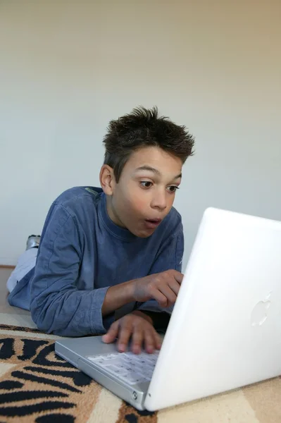 Garoto surpreso assistindo um filme em seu laptop — Fotografia de Stock