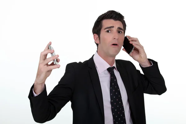 Overwhelmed businessman answering telephones — Stock Photo, Image