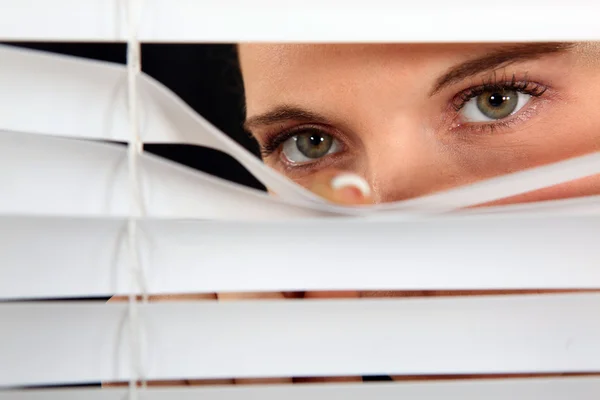 Kvinnan tittar fram genom några persienner — Stockfoto