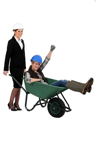 Architect pushing her colleague in wheelbarrow — Stock Photo, Image