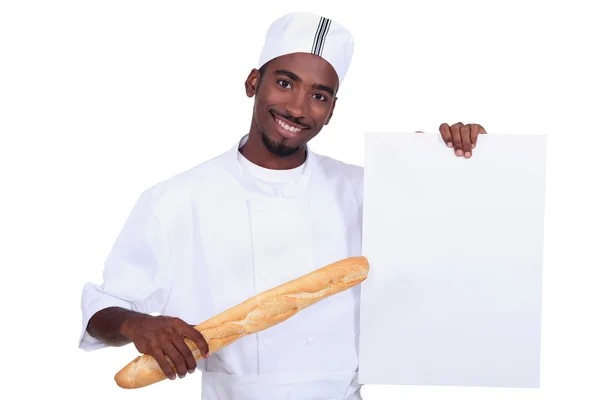 Baker com uma baguete e uma placa deixou em branco para sua mensagem — Fotografia de Stock