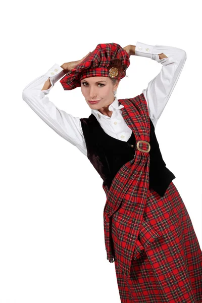 Una joven vistiendo un traje escocés y mirándonos . — Foto de Stock