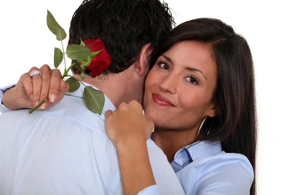 Mujer sosteniendo rosa roja soltera y abrazando marido — Foto de Stock