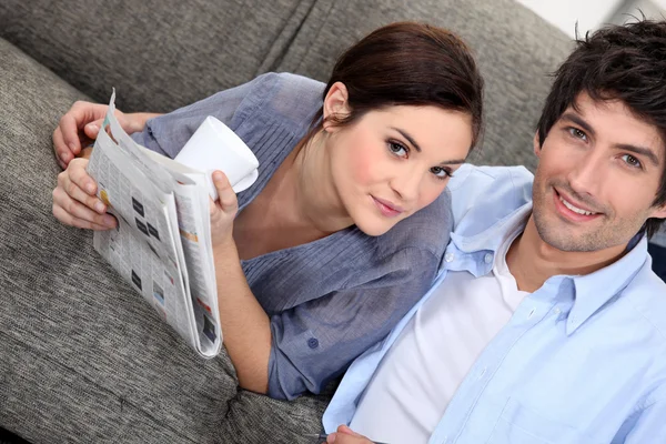 Casal lendo um jornal em casa — Fotografia de Stock