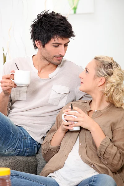 Man and woman drinking coffee on a couch — Stock Photo, Image
