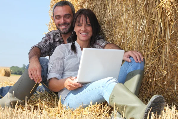 Paar entspannt mit Laptop im Stroh — Stockfoto