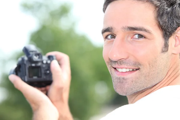 Чоловік дивиться на задню частину цифрової камери — стокове фото