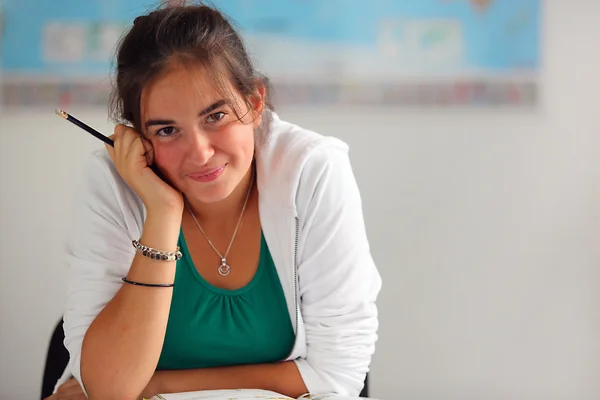 Glückliche Studentin sitzt in einem Klassenzimmer — Stockfoto