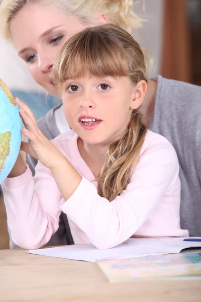 Little girl and mother looking at globe Stock Photo