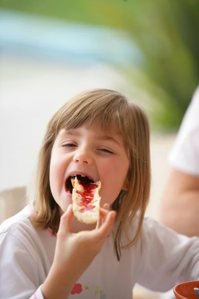 Little girl eating bread with jam on it — Stock Photo, Image