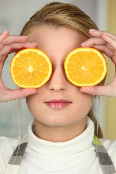 Ung kvinna med orange halvor som ögon — Stockfoto