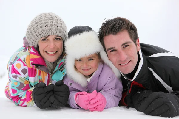 Junge Familie liegt im Schnee — Stockfoto