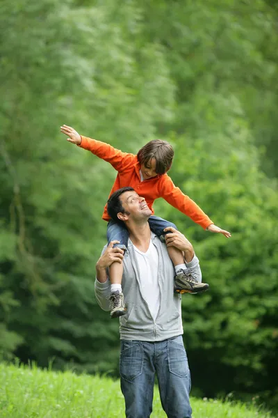 Little boy sat on father's shoulders — Stock Photo, Image