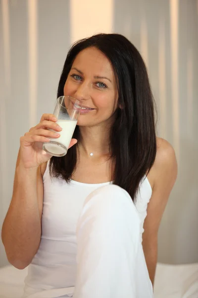 Mulher de branco bebendo um copo de leite — Fotografia de Stock
