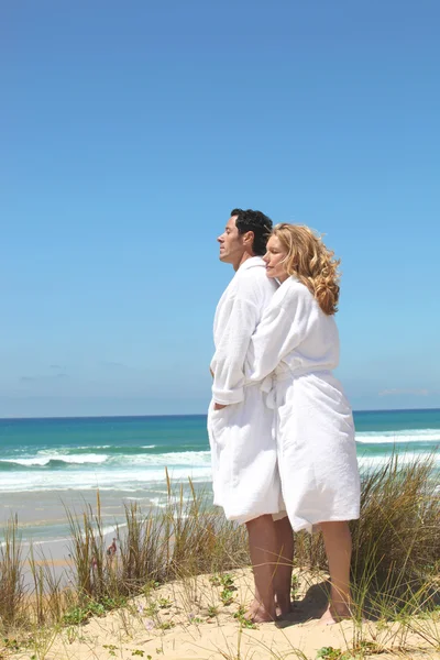 Couple in robes on the beach — Stok fotoğraf