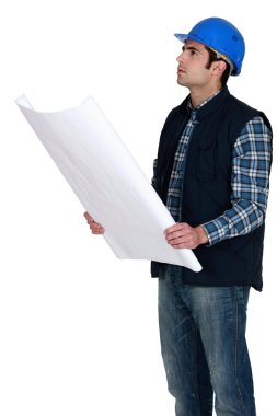 Construction worker verifying a building drawing clipart