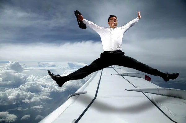 Podnikatel skáče přes křídlo letounu — Stock fotografie