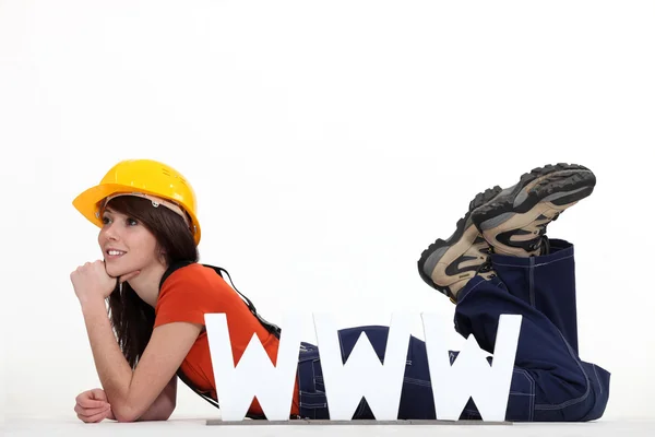 Female builder laying by large WWW letters — Stock Photo, Image