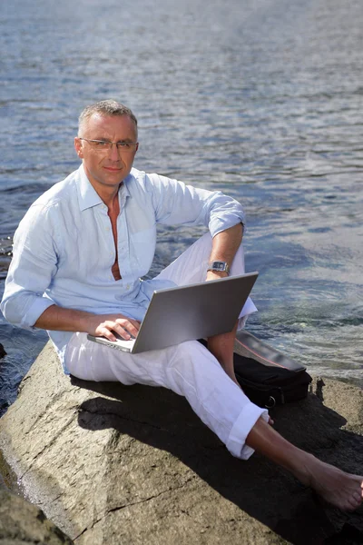 Άνθρωπος στις διακοπές που εργάζονται για το laptop του κοντά στη θάλασσα — Φωτογραφία Αρχείου