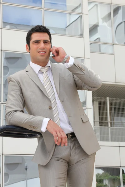 Бизнесмен стоял снаружи офиса с мобильным телефоном — стоковое фото