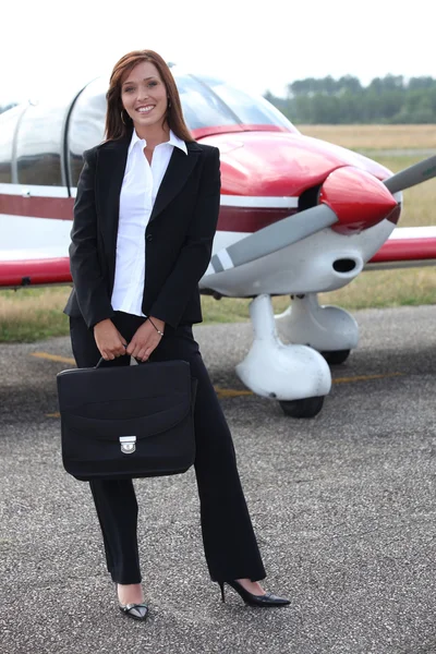 Happy businesswoman standing in front of a plane — Stock Photo, Image