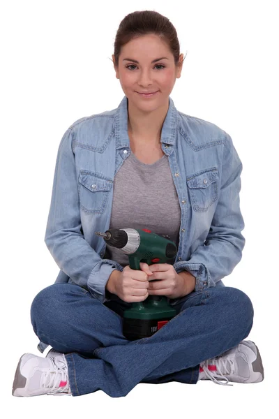 Woman sitting cross-legged and holding an electric screwdriver — Stock Photo, Image