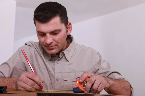 Tradesman marcatura di una misura con una matita — Foto Stock