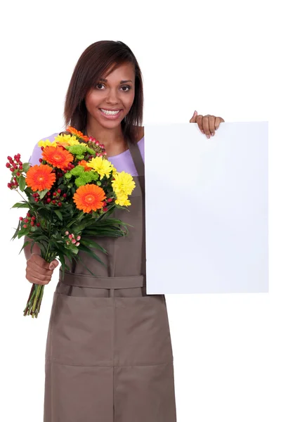 Gardener with flowers and poster — Stock Photo, Image