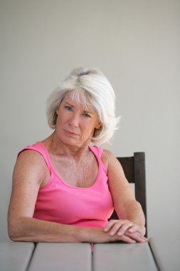 Senior woman sitting at a table clipart