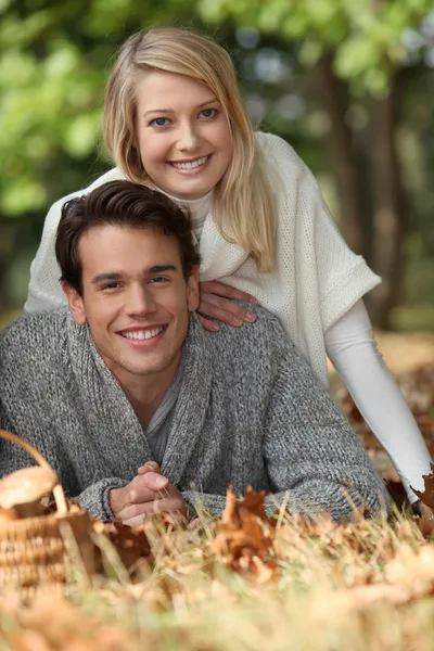 Ein junges Paar legt sich ins Gras, ein Pilzkorb liegt auf dem Boden — Stockfoto
